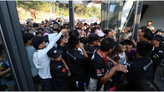 Visitantes se aglomera a la entrada del puente colgante de vidrio del gran cañón de Zhangjiajie, provincia de Hunán.