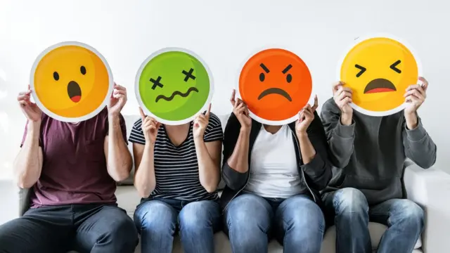 Personas con dibujos de caras con sentimientos negativos.