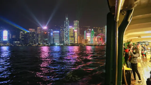 乘客在天星小輪上舉起手機拍攝維港兩岸的聖誕夜景。