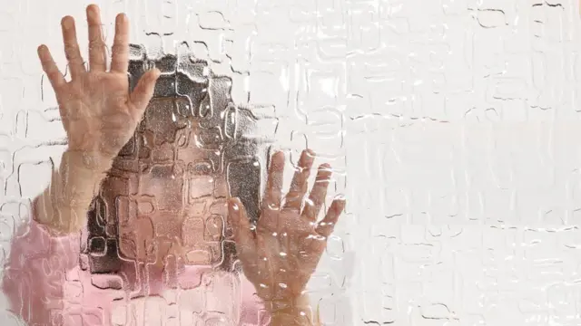 Niña tras vidrio pidiendo ayuda