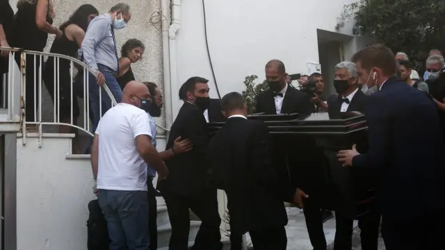 دختر میکیس تئودوراکیس (نفر پنجم از سمت چپ) و دیگر دوستان و بستگان این آهنگساز پیکر وی را از خانه اش در آتن می برند