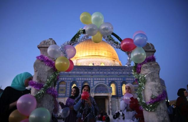 طفلات فلسطينيات ينفخن البالونات في ساحة المسجد فجر الخميس