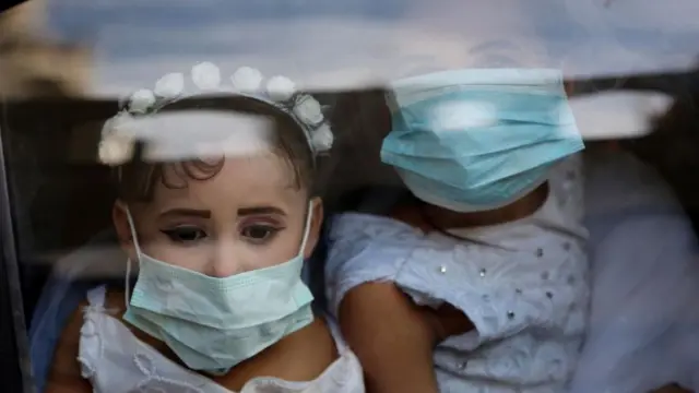 طفلتان ترتديان أقنعة واقية خلال حفل زفاف في غزة
