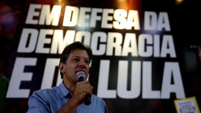 Fernando Haddad ao microfone; ao fundo, lê-se "Em defesa da democracia eproximos jogos fifa bet365Lula"