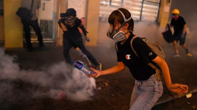 香港九龙深水埗一名女示威者躲避防暴警员发射的催泪弹（14/8/2019）