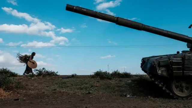 Sai kuma wata mace dake dauke da kayan amfanin gona yayin da ta doshi wata tankar mayakan Tigray da aka daina aiki da ita