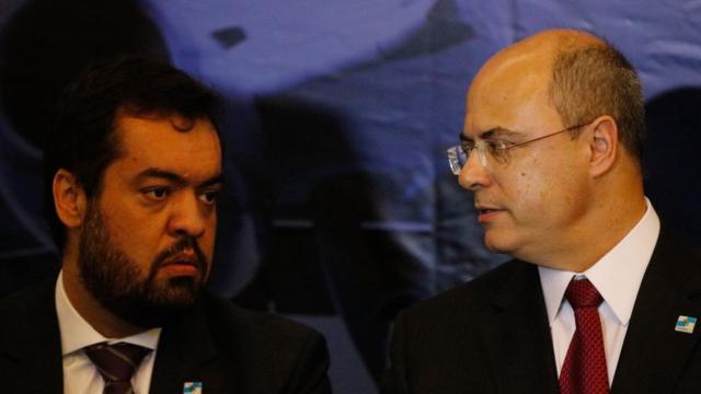 Wilson Witzel olha para Cláudio Castrosporting bet 365evento; ambos mostram feições tensas