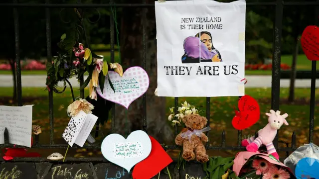 وسط باقات الزهور، وضعت صورة لرئيسة الوزراء النيوزيلندية جاسيندا أرديرن تعانق سيدة محجبة وتحتها عبارة أطلقتها جاسيندا تقول "نيوزيلندا وطنهم .. هم نحن".