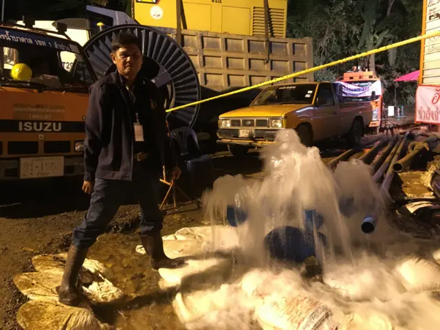 คนยืนอยู่ข้างน้ำไหลออกจากท่อ