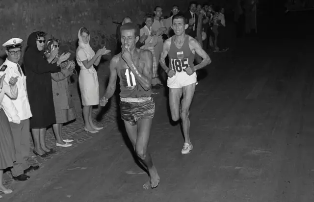 Ethiopian athlete Abebe Bikila runs barefoot ahead of another competitor