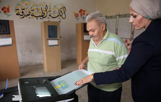 Irak'ta uygulanan elektronik seçim sisteminde seçmenler oylarını kullandıktan sonra pusulalarını ters çevirerek bir tarayıcıya sokuyor