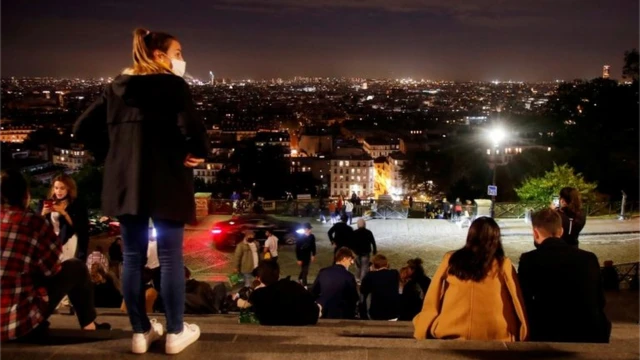 Diversos jovens sentadosescadaria com roupasfrio, à noite, diantevista da parte baixaParis