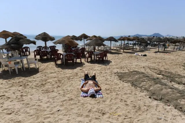 Un homme est allongé sur une plage presque déserte de Tunis.