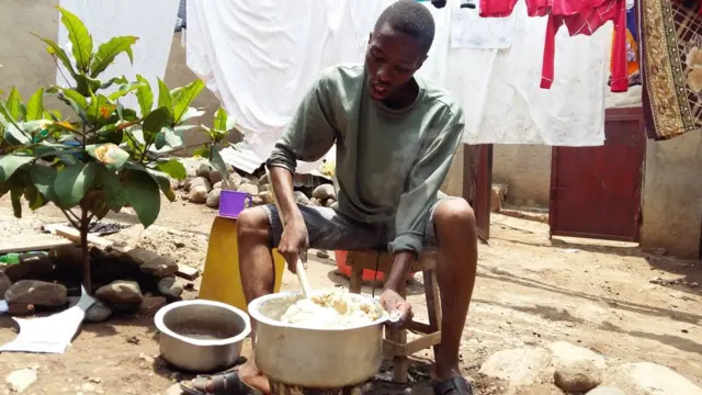 Un étudiant prépare une pâte de manioc, que ses camarades et lui vont manger avec des haricots.