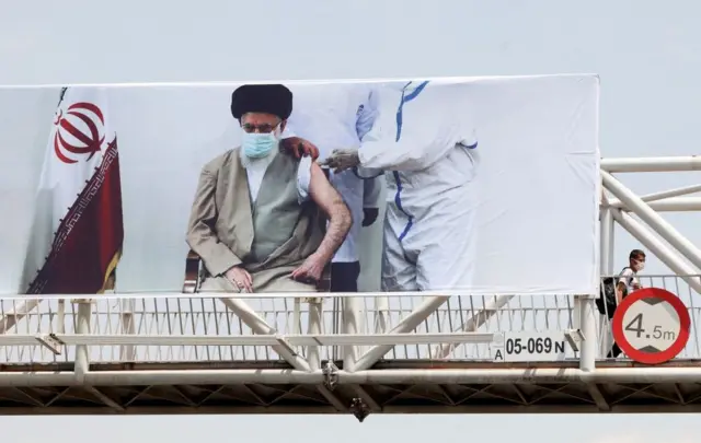 پوستر رهبر ایران در حال زدن واکسن در اقدامی که تشویق برای واکسن کووایران برکت توصیف شده است