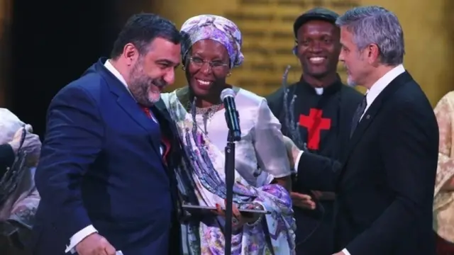 Avrora mükafatının təsisçisi (solda) Ruben Vardanyan və jüri həmsədri, amerika kino ulduzu George Clooney (sağda) ilk mükafat laureatı Marguerite Barankitse-i təbrik edirlər