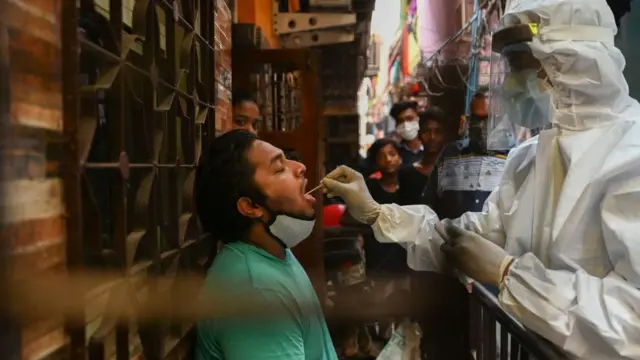 A health worker wearing protective gear takes a swab sample of a resident for a Covid-19 coronavirus test at Dharavi slum in Mumbai on March 11, 2021.
