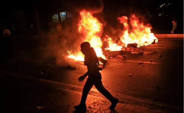 A masked protester runs past garbage bins set on fire by supporters of the pro-Kurdish Peoples"s Democratic Party (HDP) in Diyarbakir, in Turkey"s predominantly Kurdish southeast, Sunday, Nov. 1, 2015.