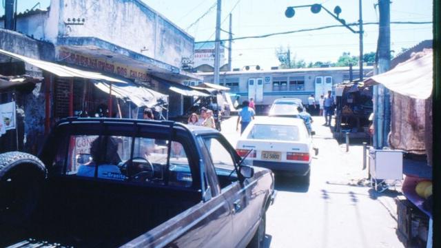 Carros aguardam passagem de trem na favela do Jacarezinho