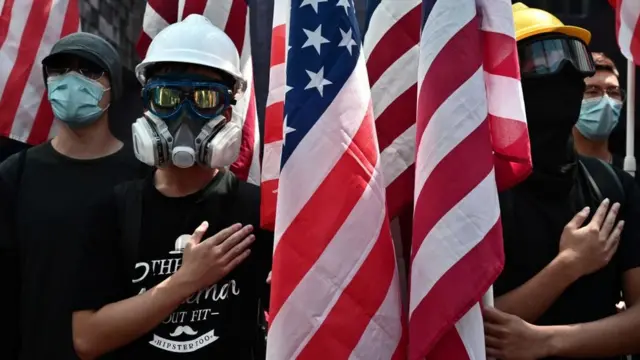 Protesters sing the Star-Spangled Banner as they march while holding the US flag at the Hong Kong University (HKU) campus