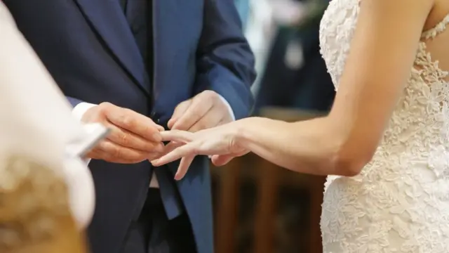 Groom putting ring on bride's finger