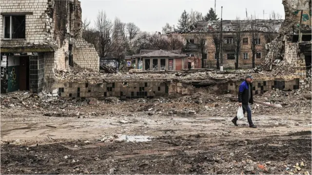 A Ukrainian walks through the ruins of damaged buildings in Borodianka