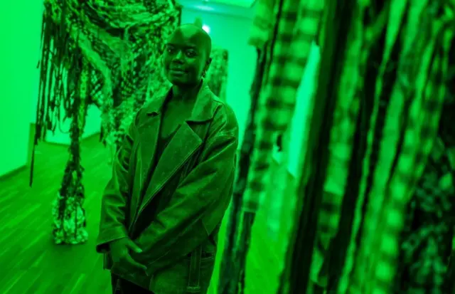 The light is green. Wata mata na tsaye a gaban aikin zane-zane a cikin dakin da ake baje kolin kayayyakin zane zane.