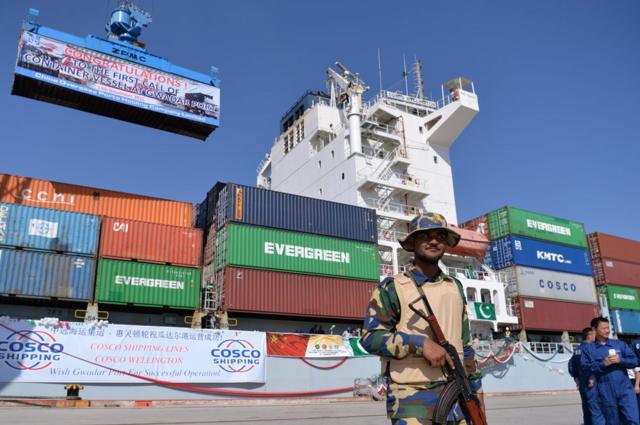 Pakistani Naval personnel stand guard near a ship carrying containers at the Gwadar Port