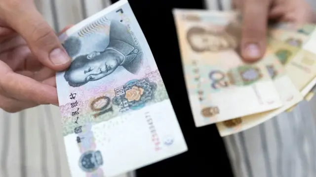 إمرأة تحمل أوراقًا ورقية من اليوان الصيني