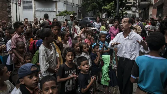 Niños esperan en un comedor.