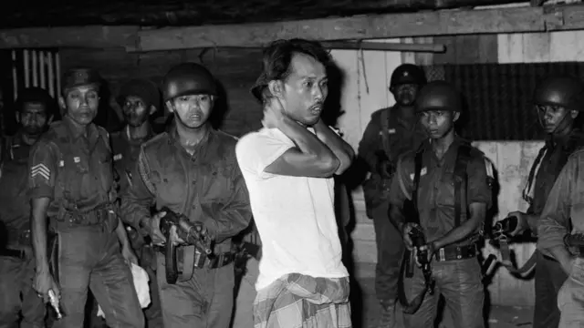 A suspected sympathizer with the Communist-led abortive coup of October 1th is questioned under gunpoint. The Indonesian Army is continuing its careful screening in an effort to uproot dissenters.