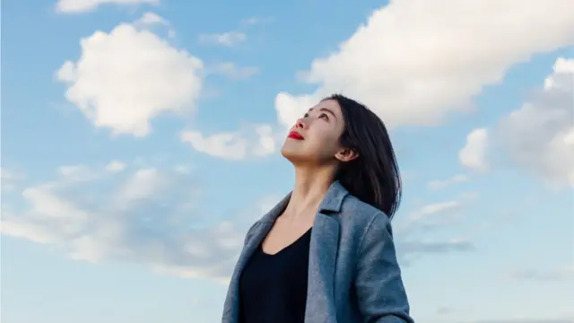 Femme en pleine réflexion, regardant vers les nuages