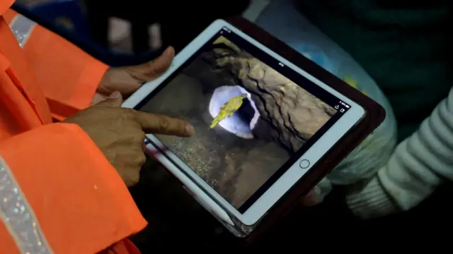 Представитель полиции показывает родственникам подростков фотографии, сделанные во время спасательной операции