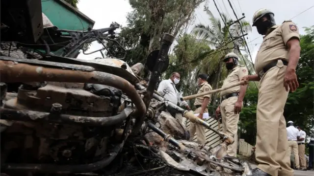 ضابط شرطة يتفقد سيارات محروقة