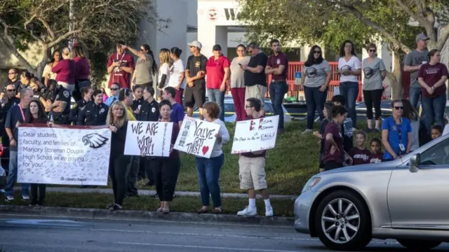 Vecinos y agentes de policía reciben a los alumnos en la puerta de la escuela.