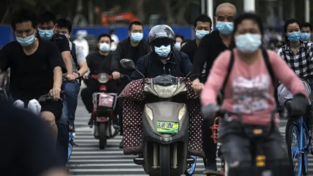 Residents wears face masks while riding their bicycles on May 11, 2020 in Wuhan, China.
