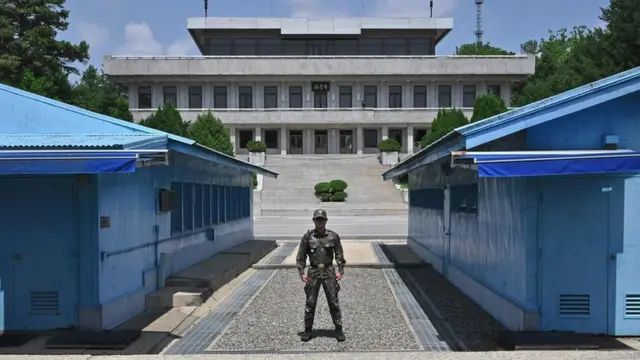 Umusirikare wa Koreya y'Ubumanuko ahagaze mu nyubakwa iri mu karere kagabura Koreya y'Uburaruko n'Ubumanuko