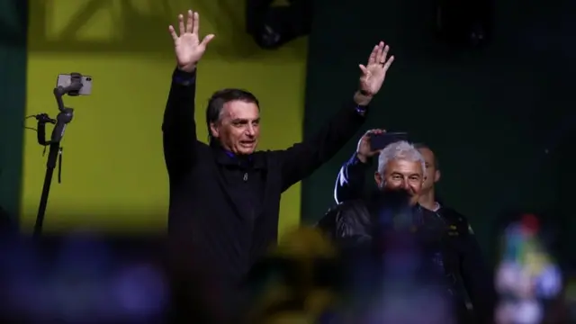 Bolsonaro acenando e sorrindoh2bet ajudacima do palco