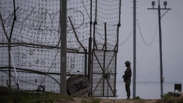 A soldier stands guard at an opening to the fence of the Demilitarized Zone (DMZ) during maintenance, on Gyodong, a tiny outlying island near to the west of Seoul, on 9 May 2017