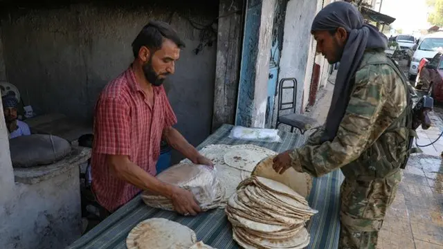Un combatiente sirio compra en un mercado en el noreste del país