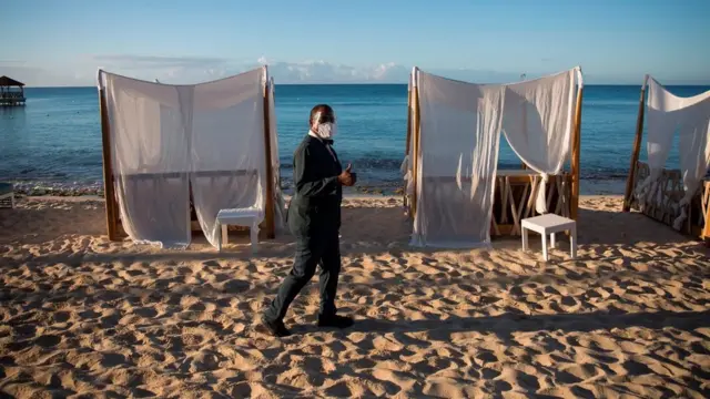 Seorang pria mengenakan masker di resor pantai yang sepi.