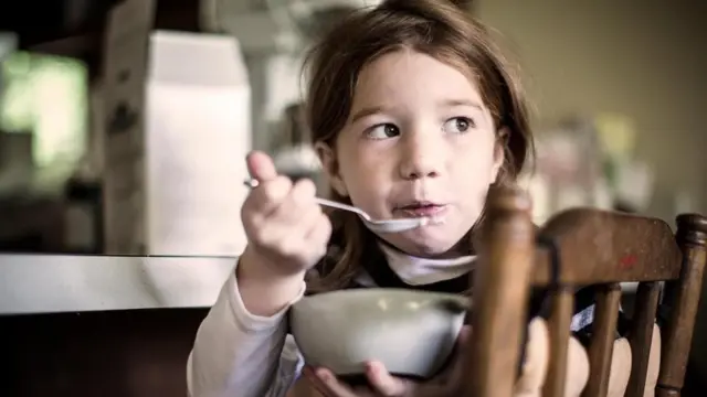Una niña comiendo de un plato de cereal