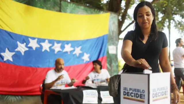 Una mujer deposita su voto durante la consulta popular realizada por la oposición el domingo.