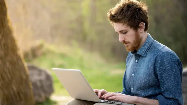 Em parque, homem trabalha sozinho com notebook