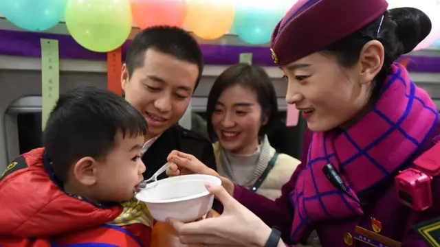 中国高铁的乘务员在一列列车上为旅客送上汤圆，欢度佳节