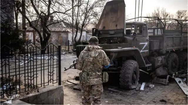 A Ukrainian serviceman stands near a Russian army truck in the north-eastern city of Trostianets