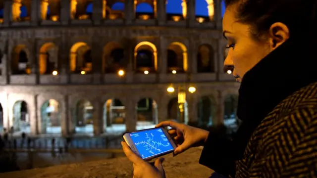 Mulher observa celular à noite