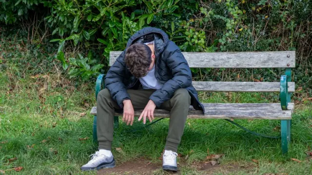 Un joven cabizbajo sentado en un banco