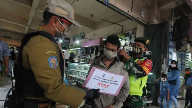 Anggota Satuan Polisi Pamong Praja Kota Salatiga dan personel TNI memberikan masker kepada warga yang tidak menggunakan masker saat patroli edukasi protokol kesehatan di Pasar Raya II, Salatiga, Jawa Tengah, Rabu (20/05)