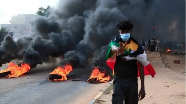 متظاهر سوداني يحمل علم البلاد.